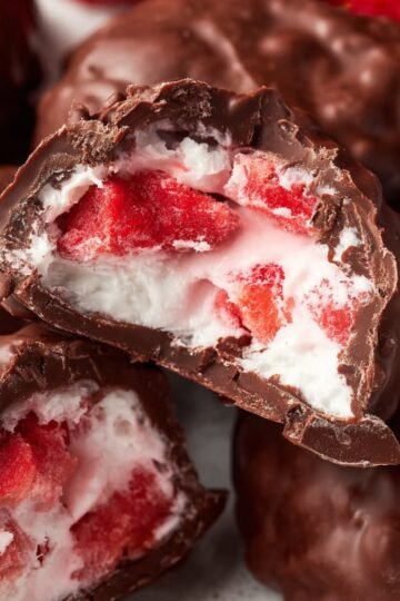 Healthy Chocolate Strawberry Yogurt Clusters 15 Close up of a Chocolate Strawberry Yogurt Clusters, showing a bite taken out revealing the creamy yogurt and vibrant red strawberries inside, surrounded by a glossy layer of dark chocolate.