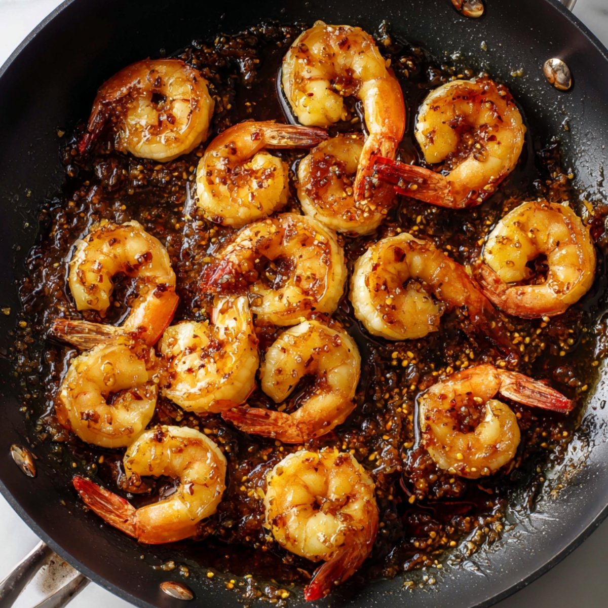Delicious Honey Garlic Shrimp Recipe 11 Honey garlic shrimp cooking in a pan with a glossy sauce and browned shrimp.