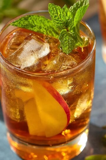 Healthy Apple Iced Tea Recipe 4 A refreshing glass of apple iced tea with ice cubes, a slice of apple, and mint leaves, ready to be enjoyed on a hot day.