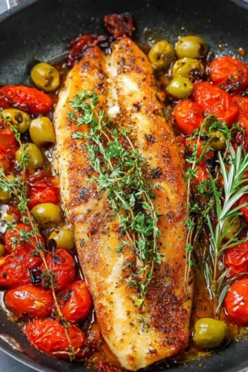 Easy Baked Fish with Cherry Tomatoes and Olives Recipe 21 Baked fish with cherry tomatoes and olives, green olives, and fresh herbs in a pan.