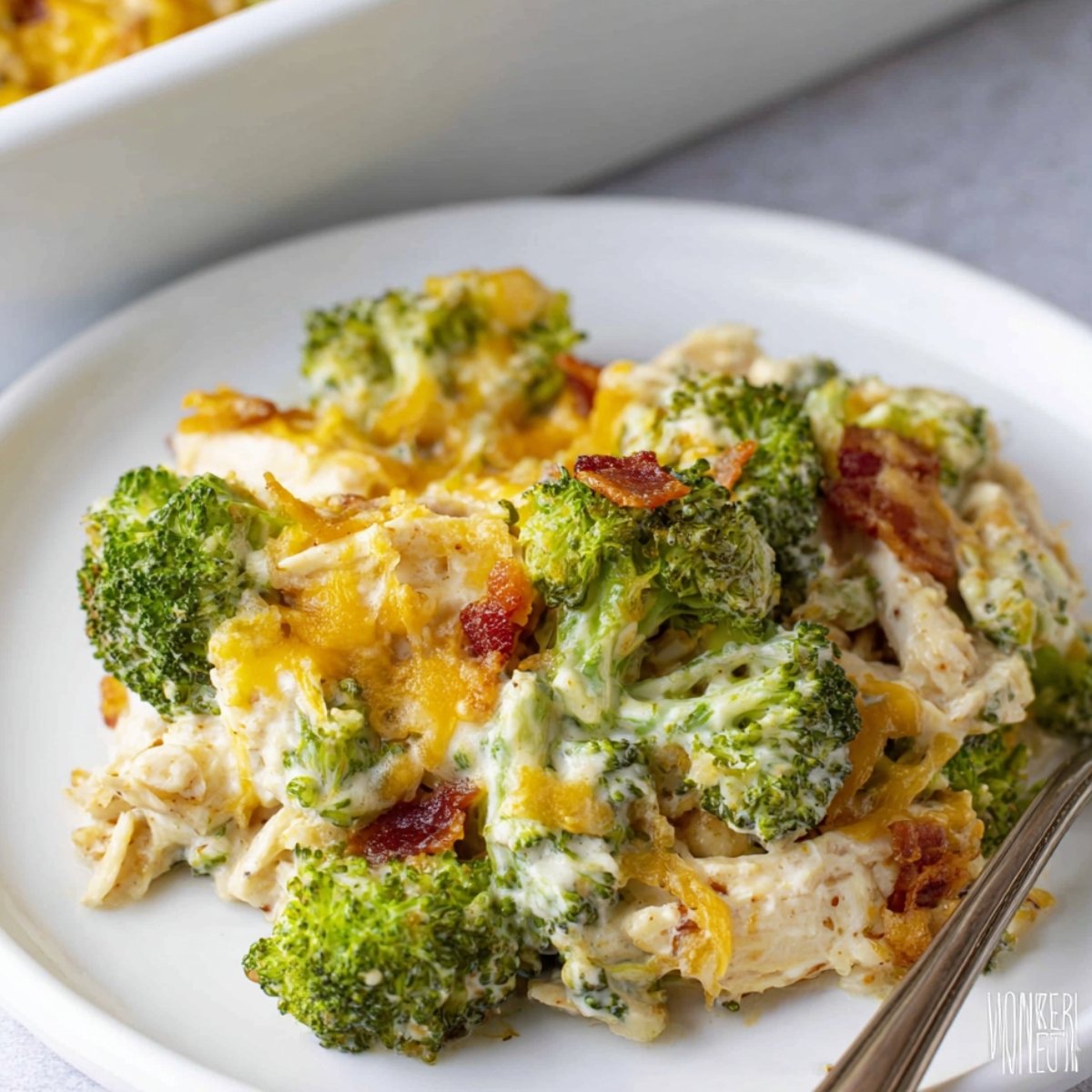 Easy Chicken Bacon Ranch Casserole Recipe 9 This image shows a serving of Chicken Bacon Ranch Casserole with broccoli, melted cheese, and bacon bits on a plate.