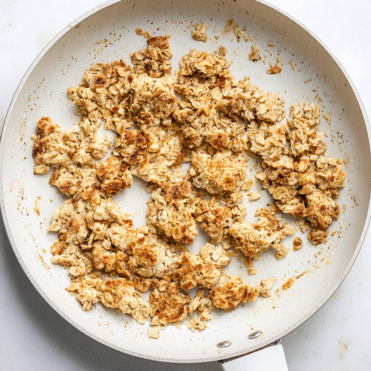 Easy Scrambled Oats Recipe 11 The image shows toasted oats in a pan, likely being cooked or browned for a recipe.