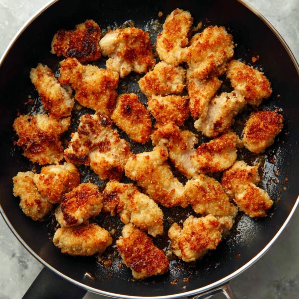 Easy Honey Butter Chicken 10 Golden crispy pieces of chicken cooking in a pan.