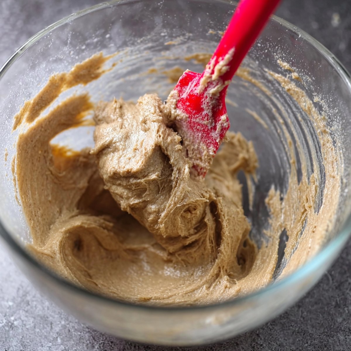 Easy Salted Caramel Macarons Recipe 10 bowl of caramel-colored frosting being mixed with a red spatula.
