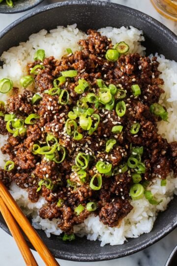Easy Korean Beef Bowl Recipe 10 A Korean Beef Bowl with ground beef, garnished with sesame seeds and green onions, served over white rice.