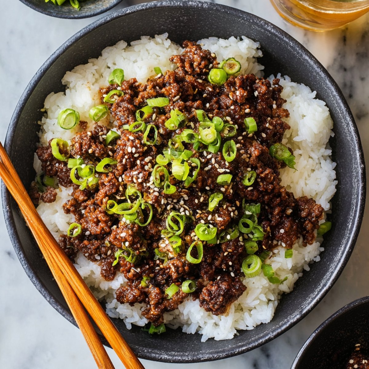 A Korean Beef Bowl with ground beef, garnished with sesame seeds and green onions, served over white rice.