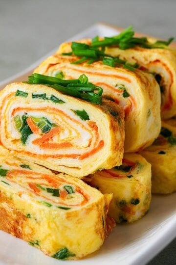 Easy Korean Rolled Omelette 17 A plate of sliced Korean Rolled Omelette with vegetables inside.