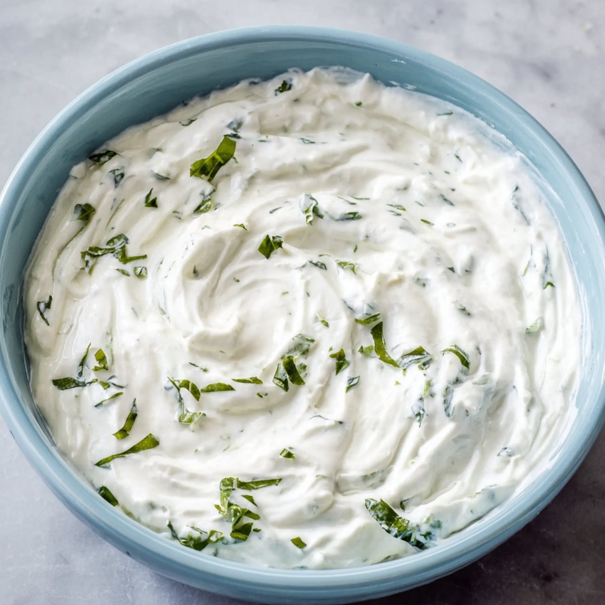 Best Turkish Eggs Recipe 10 A bowl of creamy yogurt with fresh chopped herbs mixed in.