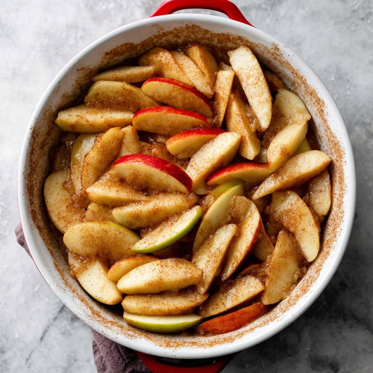 Best Apple Pie Recipe With a Buttery Flaky Crust 10 The image shows sliced apples sprinkled with cinnamon, ready to be baked.