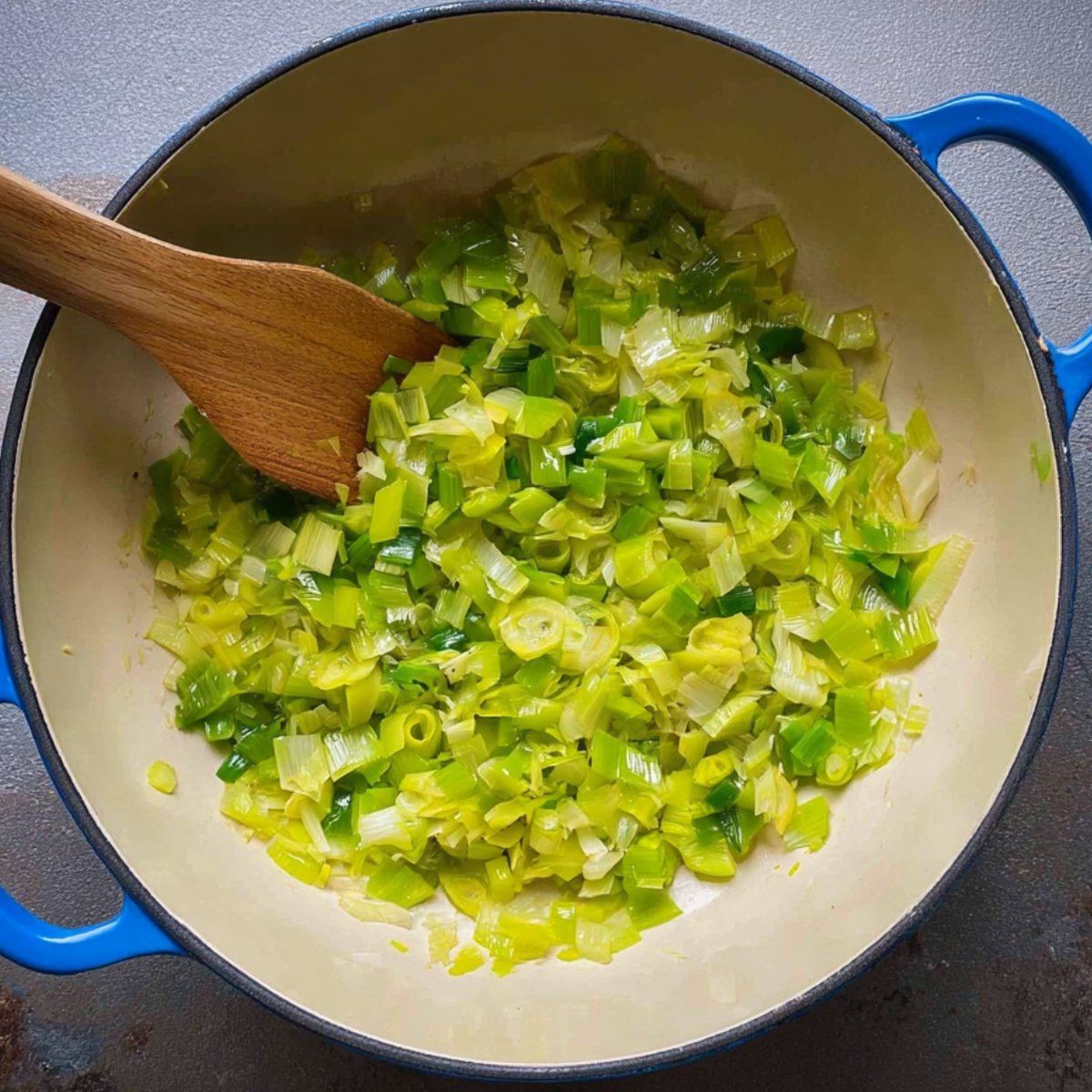 Easy Turmeric Rice with Chickpeas 10 Sautéed leeks in a pot with a wooden spoon.