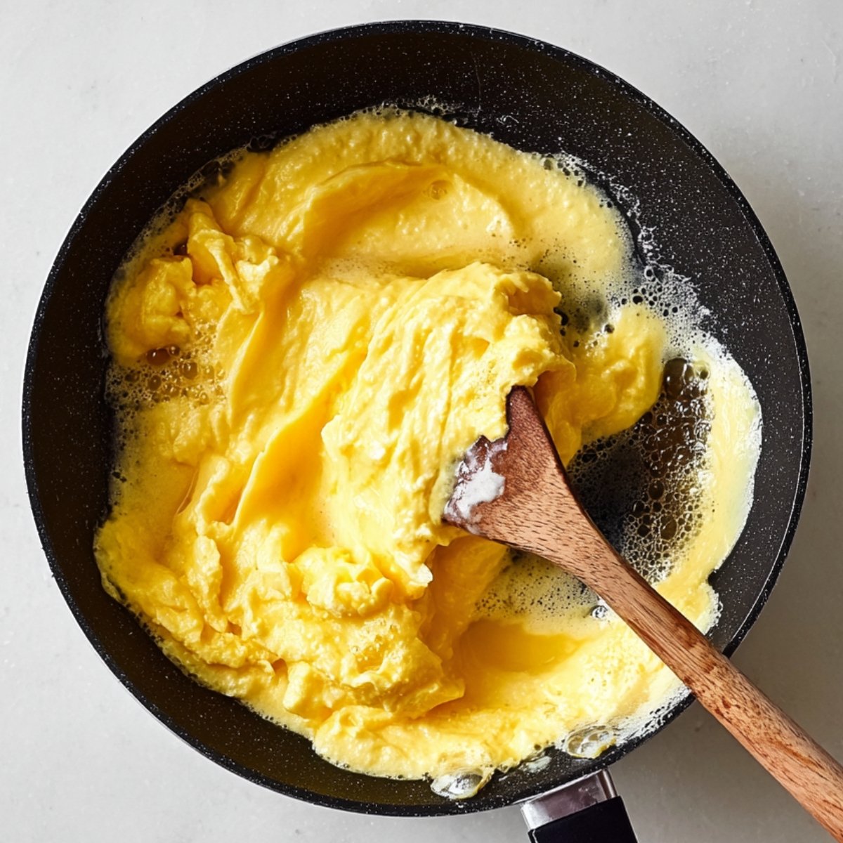 Easy Spinach Mushroom Egg Scramble 11 Creamy scrambled eggs being stirred in a frying pan.