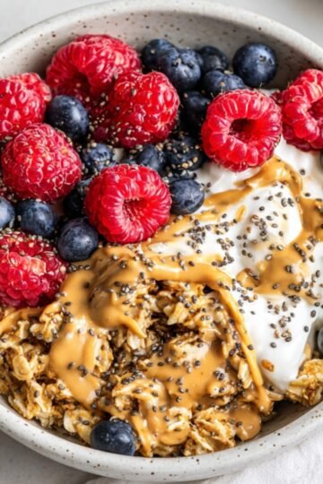 Easy Scrambled Oats Recipe 1 The image shows a bowl Scrambled Oats of oatmeal topped with yogurt, peanut butter, chia seeds, blueberries, and raspberries.