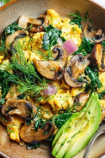 Easy Spinach Mushroom Egg Scramble 15 A delicious Spinach mushroom egg scramble, garnished with fresh dill and avocado slices.