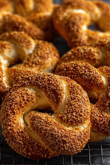 Easy Turkish Simit Recipe 20 Freshly baked Turkish simit, covered in sesame seeds, cooling on a wire rack.