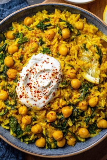 Easy Turmeric Rice with Chickpeas 23 A bowl of Turmeric Rice with Chickpeas , spinach, and a dollop of yogurt, topped with paprika and a lemon wedge.