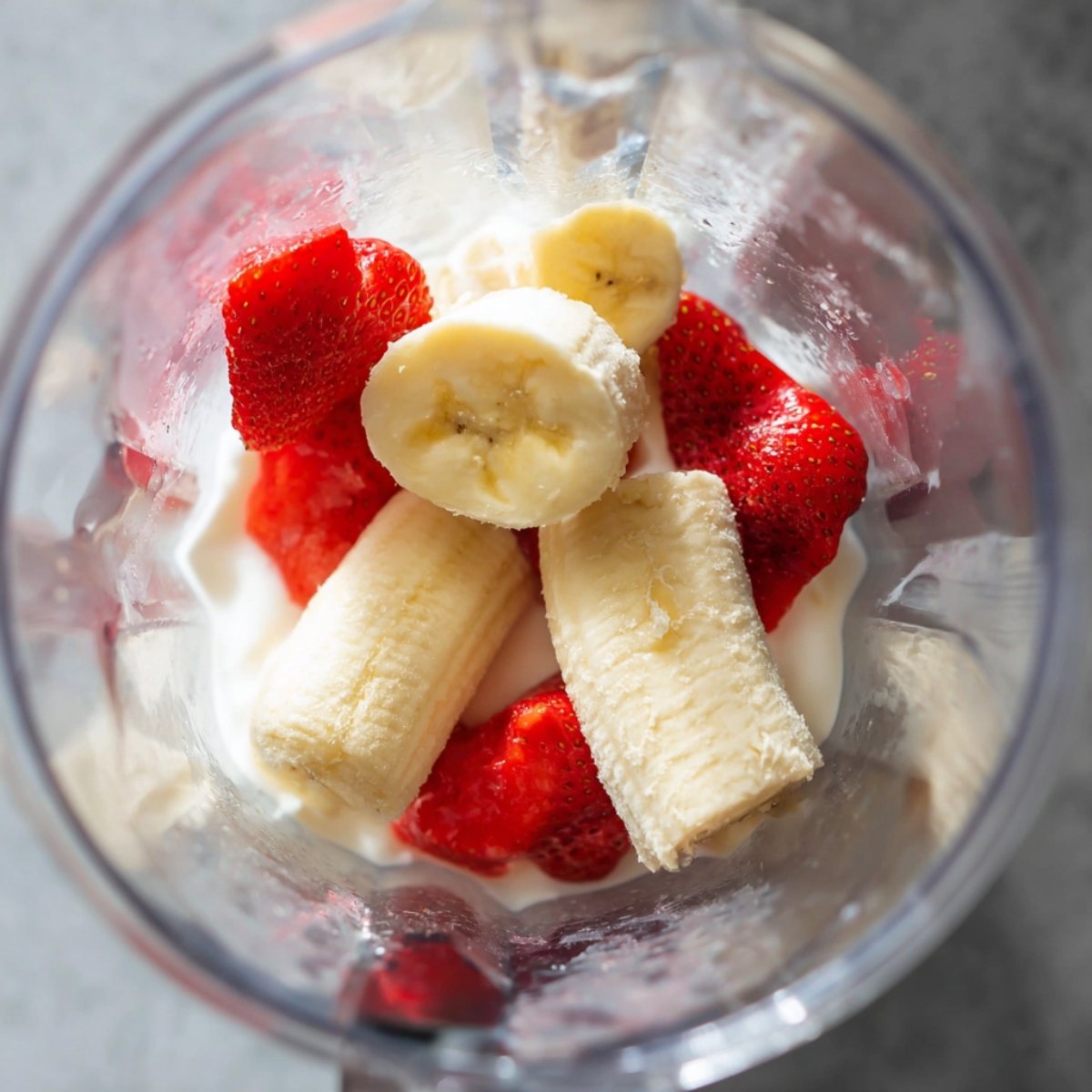 Best Strawberry Banana Smoothie Bowl 10 Sliced bananas and strawberries in a blender with milk.