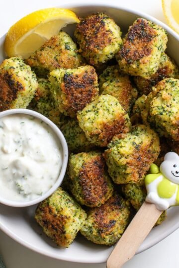 Easy Broccoli Tots Recipe 2 Golden-brown Broccoli Tots served with dipping sauce and lemon wedges.