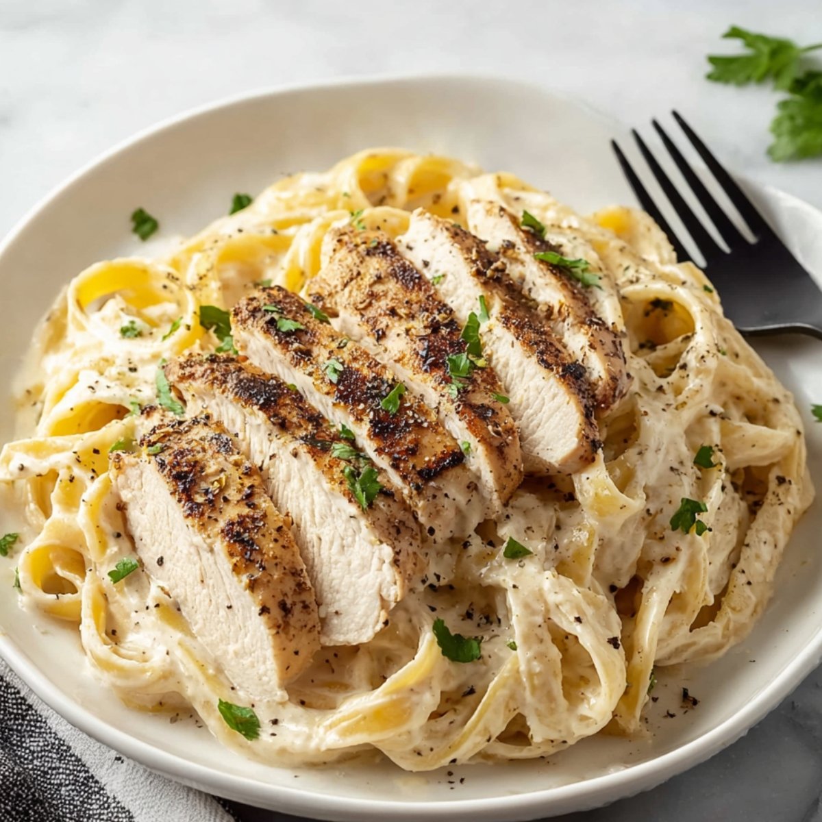 Plate of Chicken Alfredo Pasta with sliced grilled chicken.