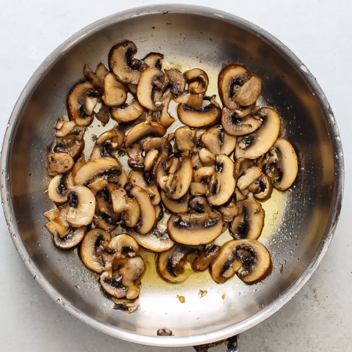 Easy Alice Springs Chicken Recipe 10 Sautéed sliced mushrooms in a skillet with oil.