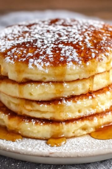 Best Cottage Cheese Pancakes 15 Image of a stack of fluffy Cottage Cheese Pancakes drizzled with syrup.