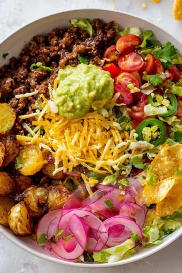 Best Crispy Potato Taco Bowls with Ground Turkey 7 Crispy Potato Taco Bowls with seasoned potatoes, ground beef, guacamole, cheese, tomatoes, jalapeños, and pickled onions.