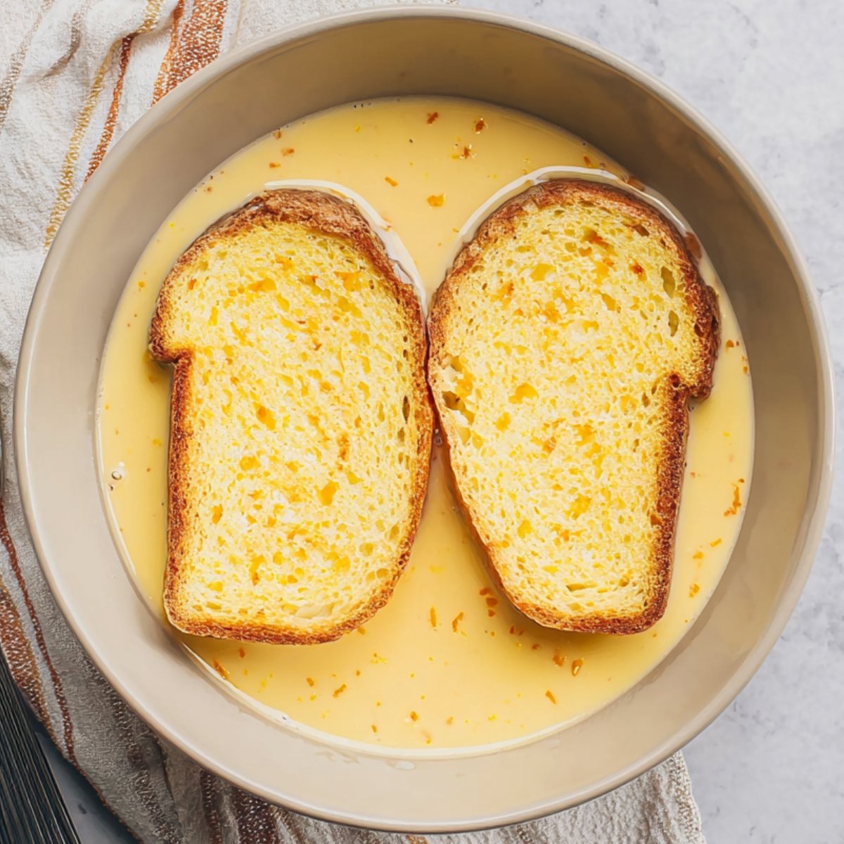 Easy Orange French Toast 11 A dish with slices of bread soaking in a custard mixture.