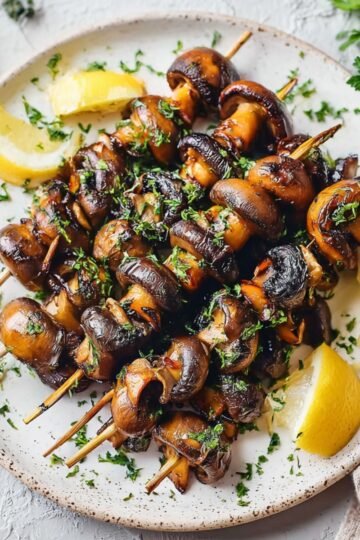 Easy Grilled Mushroom Skewers 5 Cooked Grilled Mushroom Skewers garnished with herbs and lemon