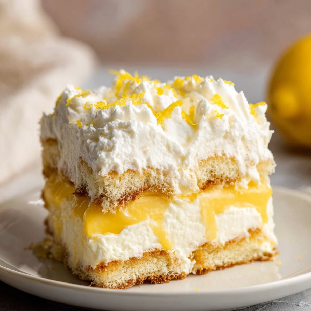 Slice of lemon tiramisu with whipped cream and lemon zest.