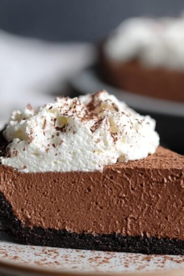 Easy No Bake Nutella Cheesecake Recipe 16 Slice of No Bake Nutella Cheesecake topped with whipped cream and grated chocolate.