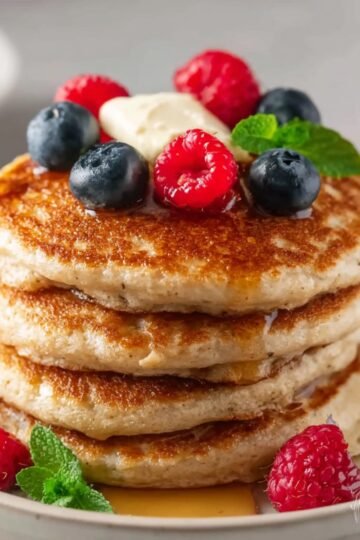 Easy Oat Flour Pancakes 16 Stack of Oat Flour Pancakes topped with berries and mint.