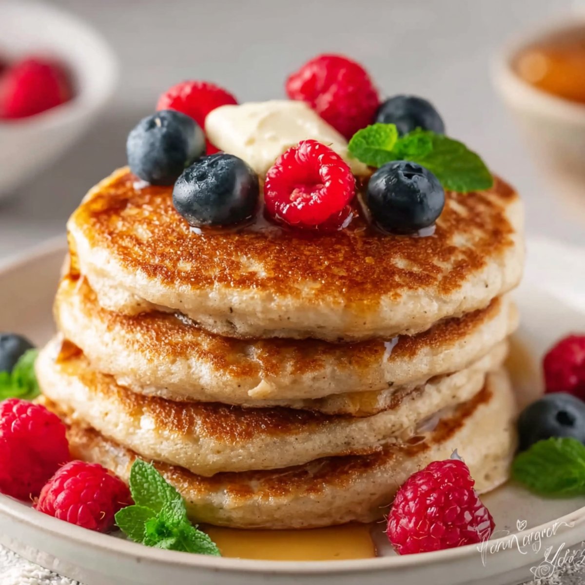 Stack of Oat Flour Pancakes topped with berries and mint.