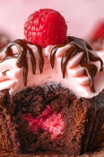 Best Raspberry Chocolate Cupcakes from Scratch 6 Raspberry chocolate cupcakes with pink frosting, chocolate drizzle, and fresh raspberry.