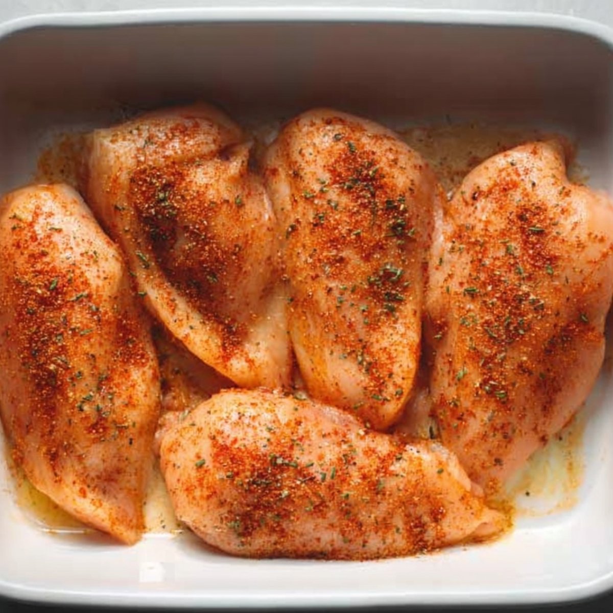 Easy Chicken Fajita Casserole Recipe 10 Raw chicken breasts seasoned with spices in a baking dish.