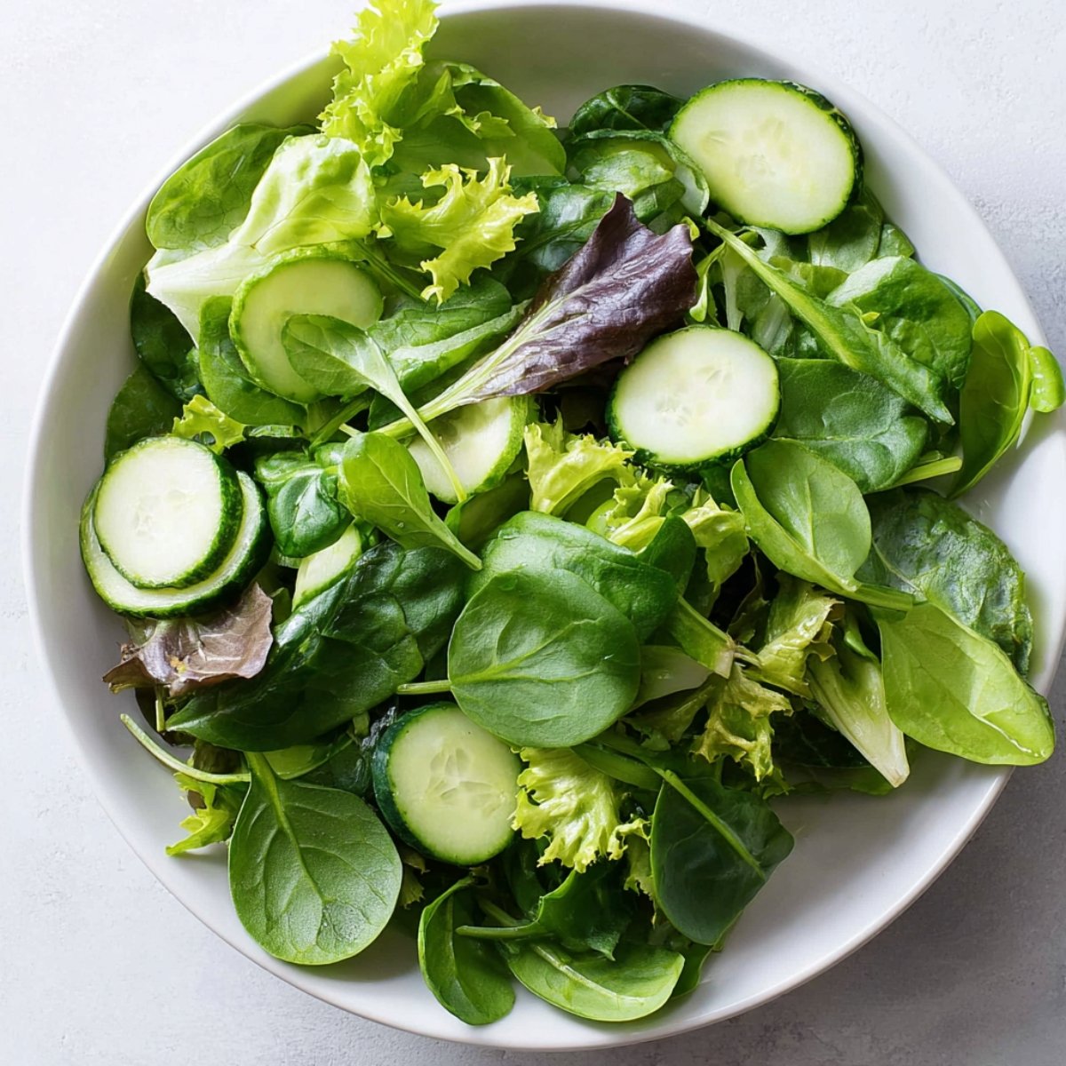 Easy Smoked Salmon Salad with Lemon Dill Dressing 11 Bowl of fresh mixed greens with cucumber slices.