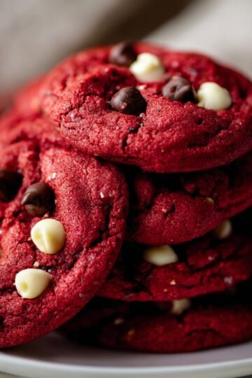 Easy Chewy Red Velvet Chocolate Chip Cookies From Scratch 16 Freshly baked red velvet chocolate chip cookies stacked on a plate.