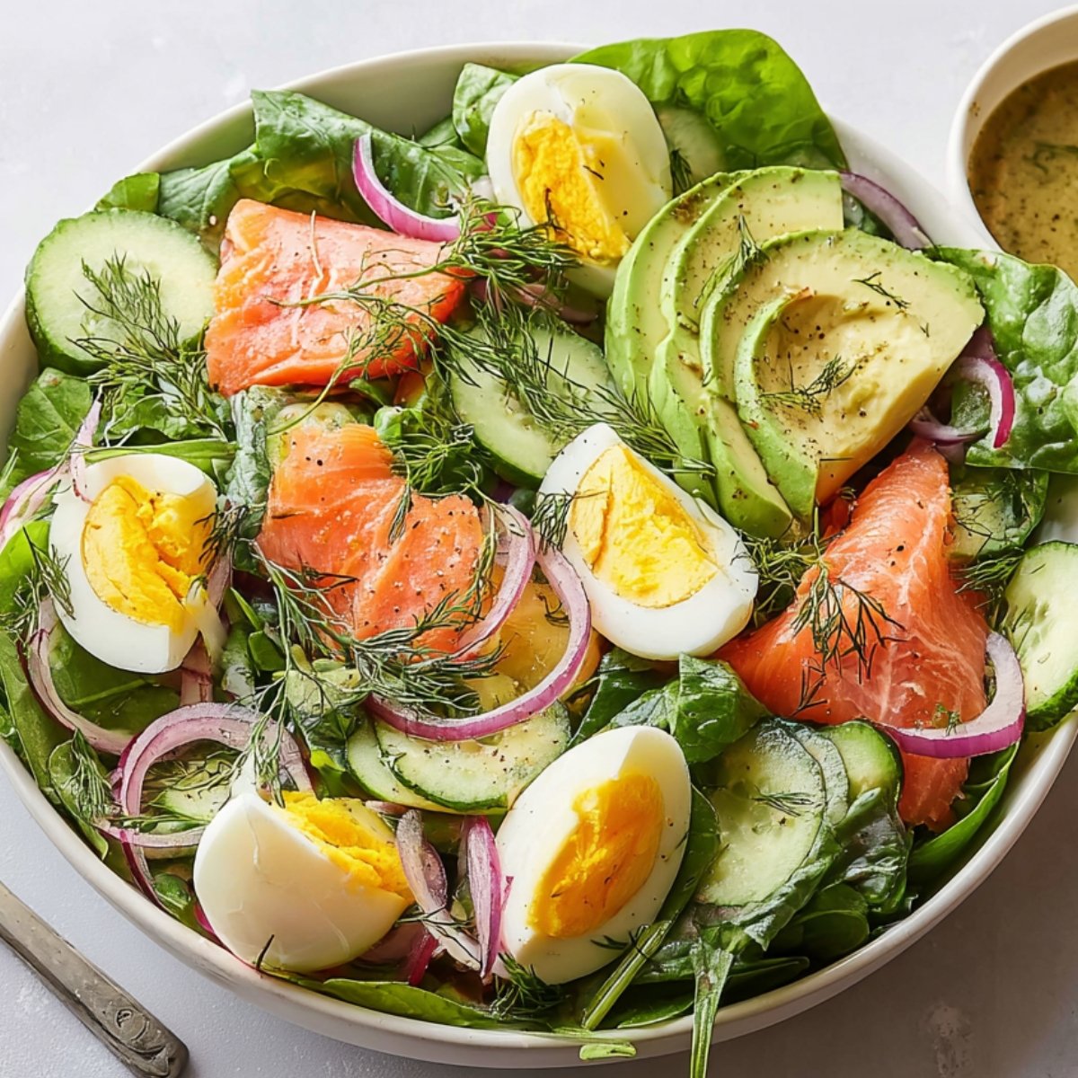 smoked salmon salad with spinach, cucumber, avocado, smoked salmon, hard-boiled eggs, red onion, and dill.